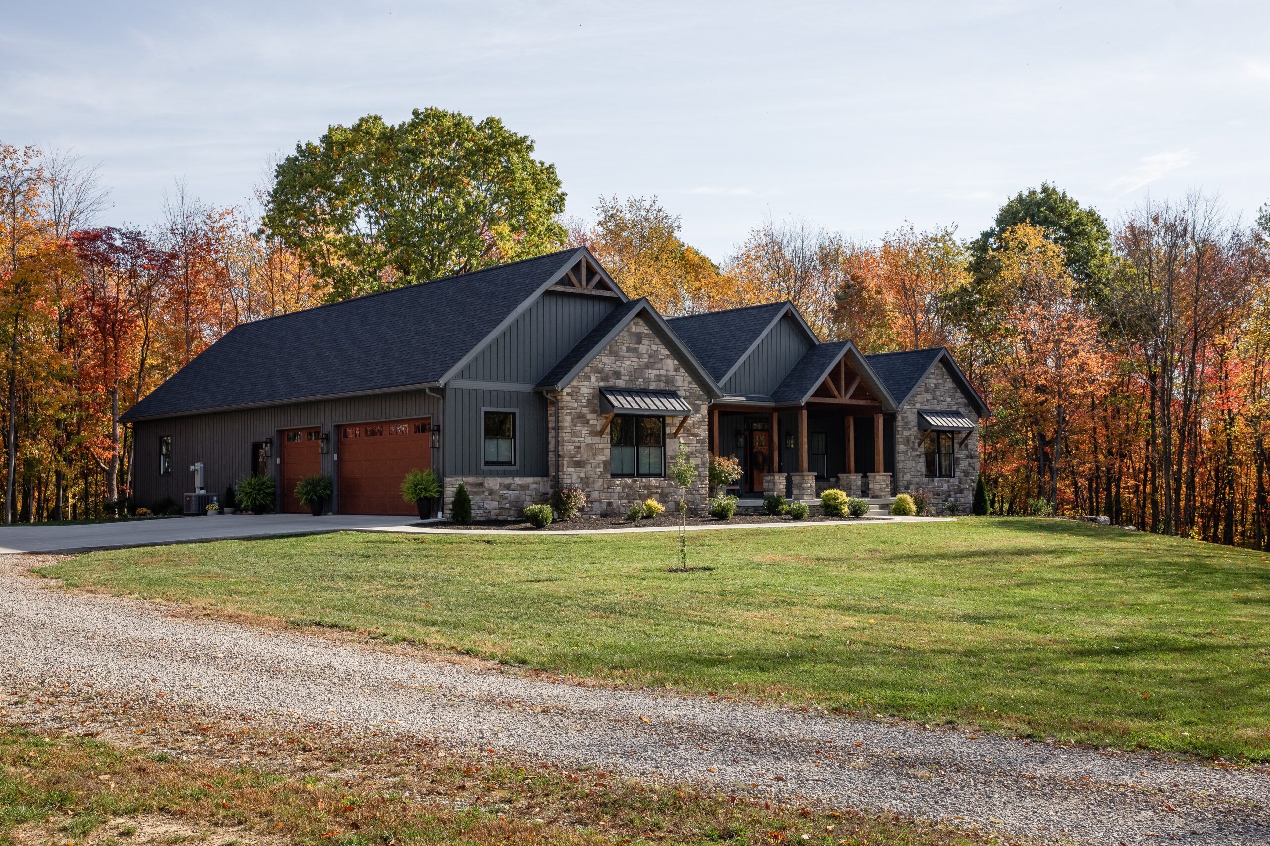 View of custom luxury home surrounded by trees and pasture