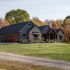 View of custom luxury home surrounded by trees and pasture