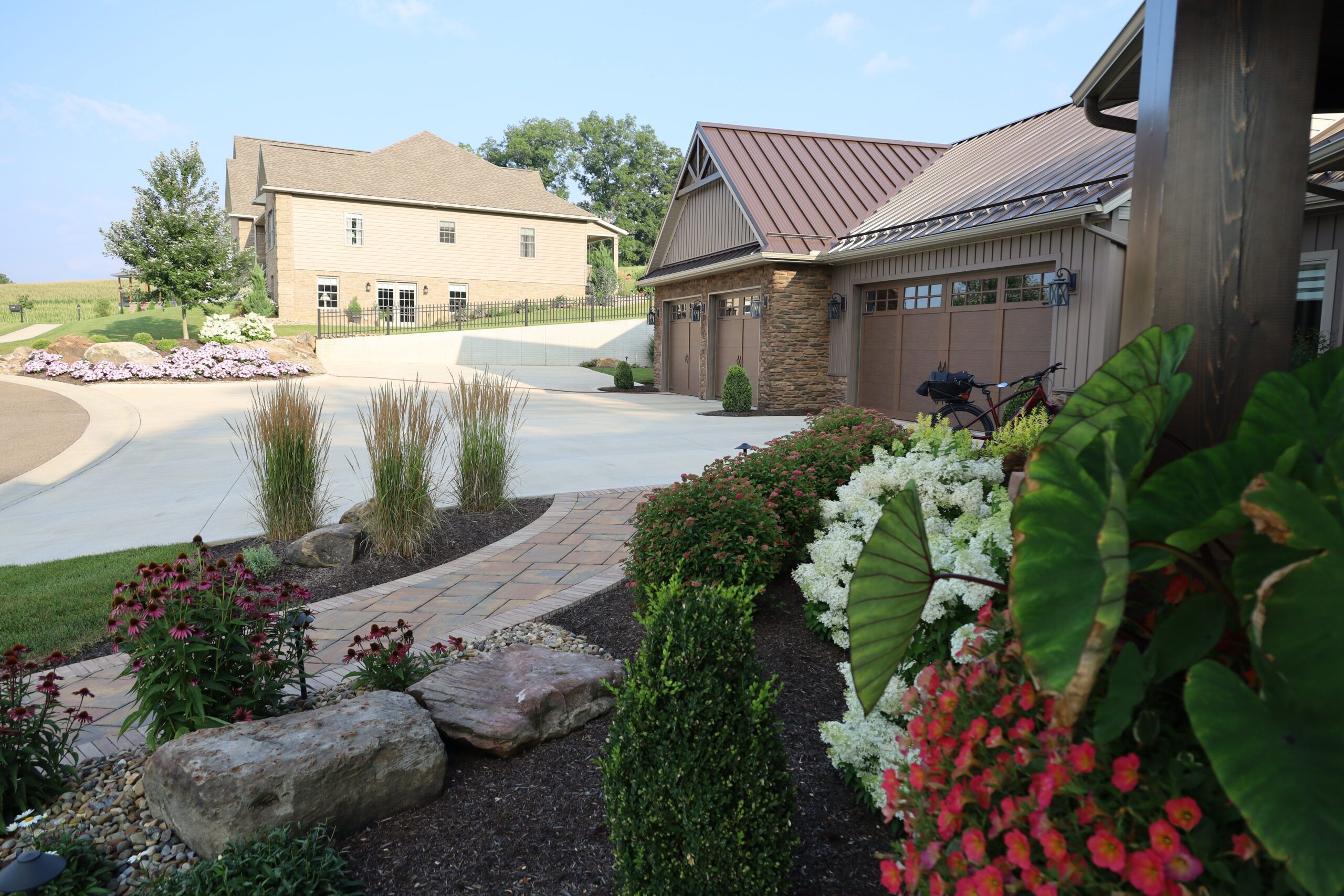 Side view of custom built home with large driveway and lush landscaping