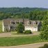 View of custom luxury home surrounded by trees and pasture