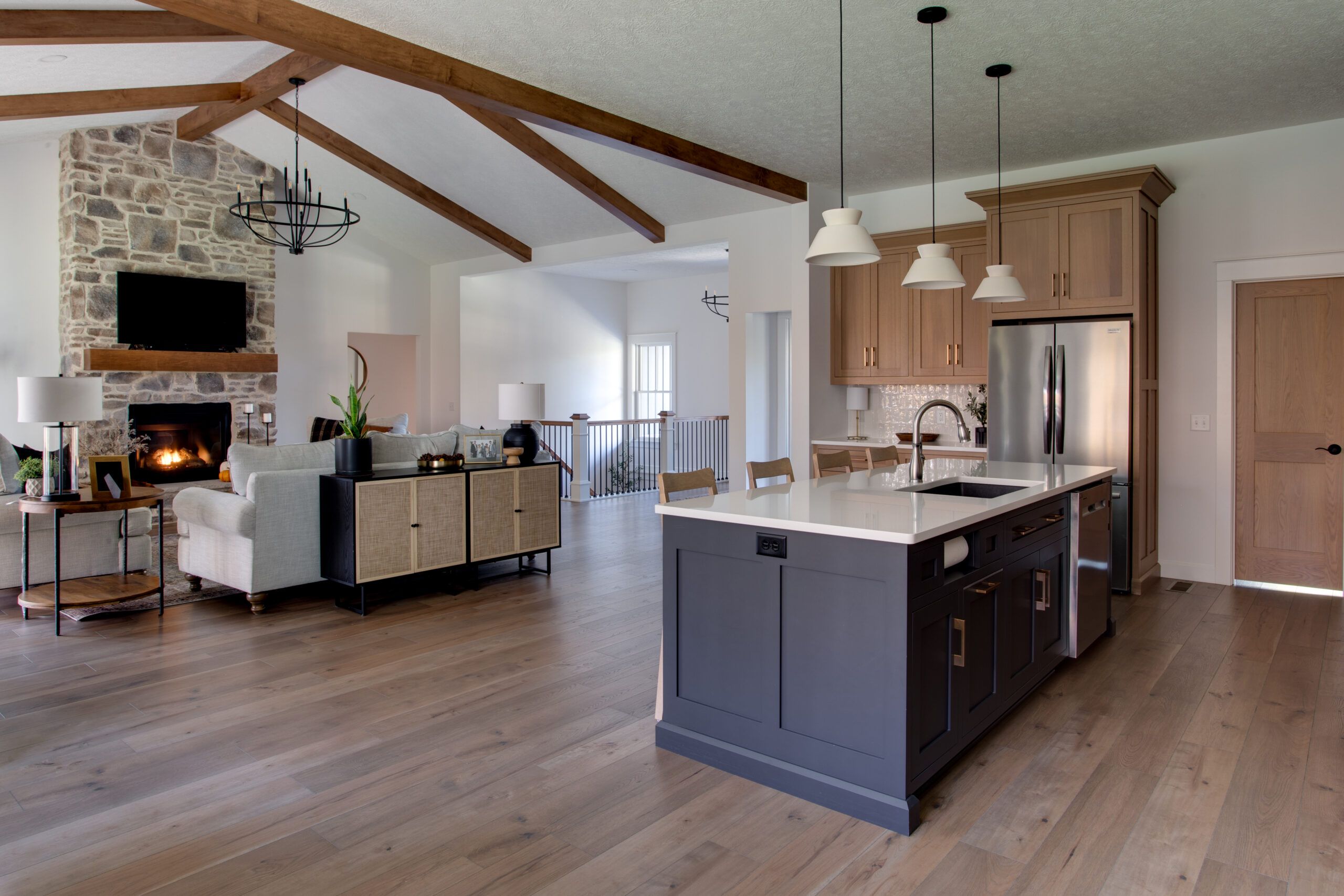 A clean kitchen with an island and bar stools, sparkling light fixtures overhead