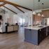 A clean kitchen with an island and bar stools, sparkling light fixtures overhead