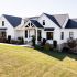 Side view of custom built home with large driveway and lush landscaping