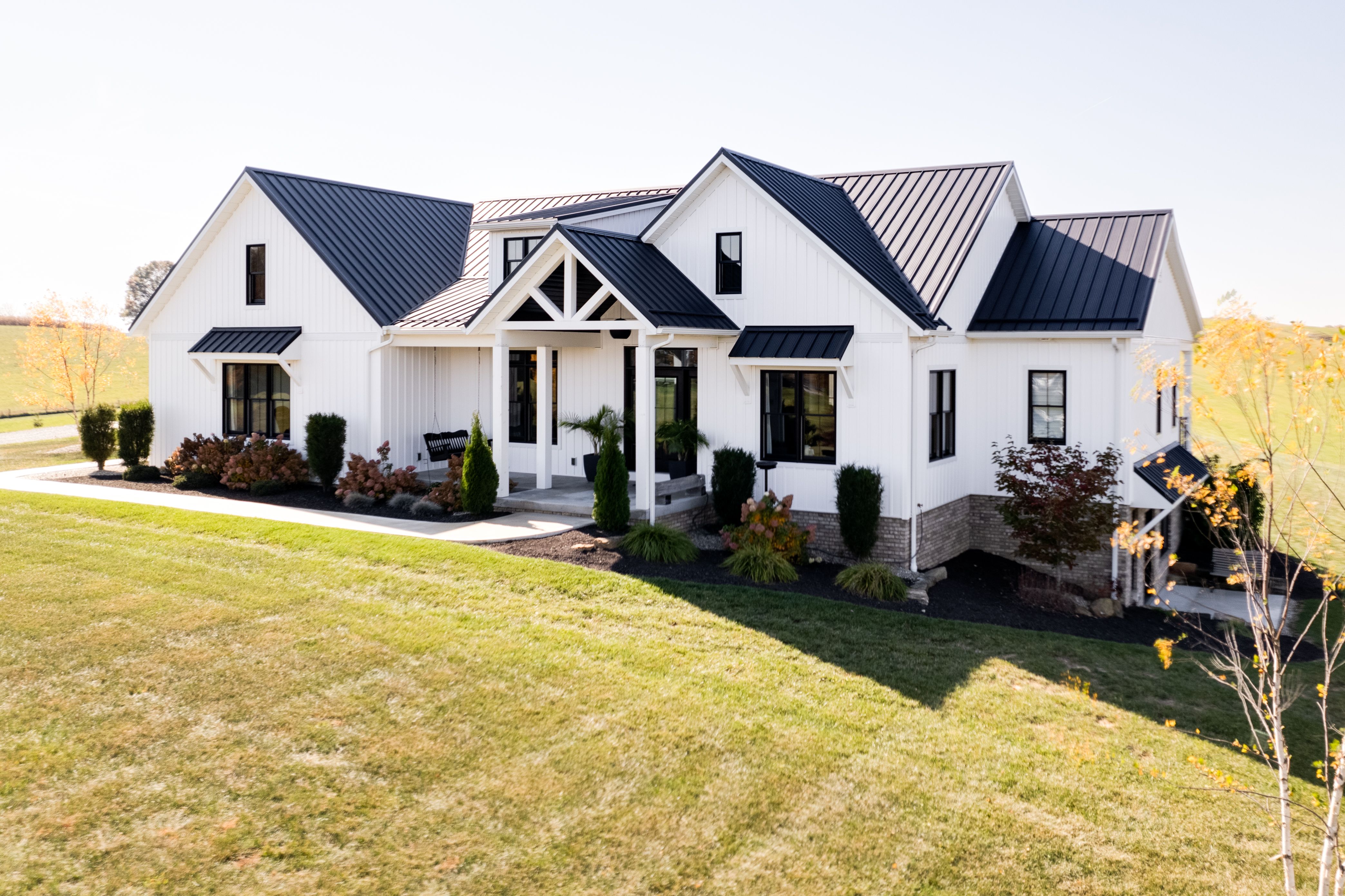 Side view of custom built home with large driveway and lush landscaping